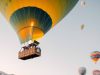 couple holding hands with hot air balloons flying around in cappadocia