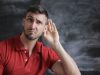 man in red polo shirt sitting near chalkboard