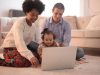 photo of family sitting on floor while using laptop