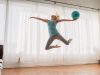 slim woman in sportswear jumping up with ball